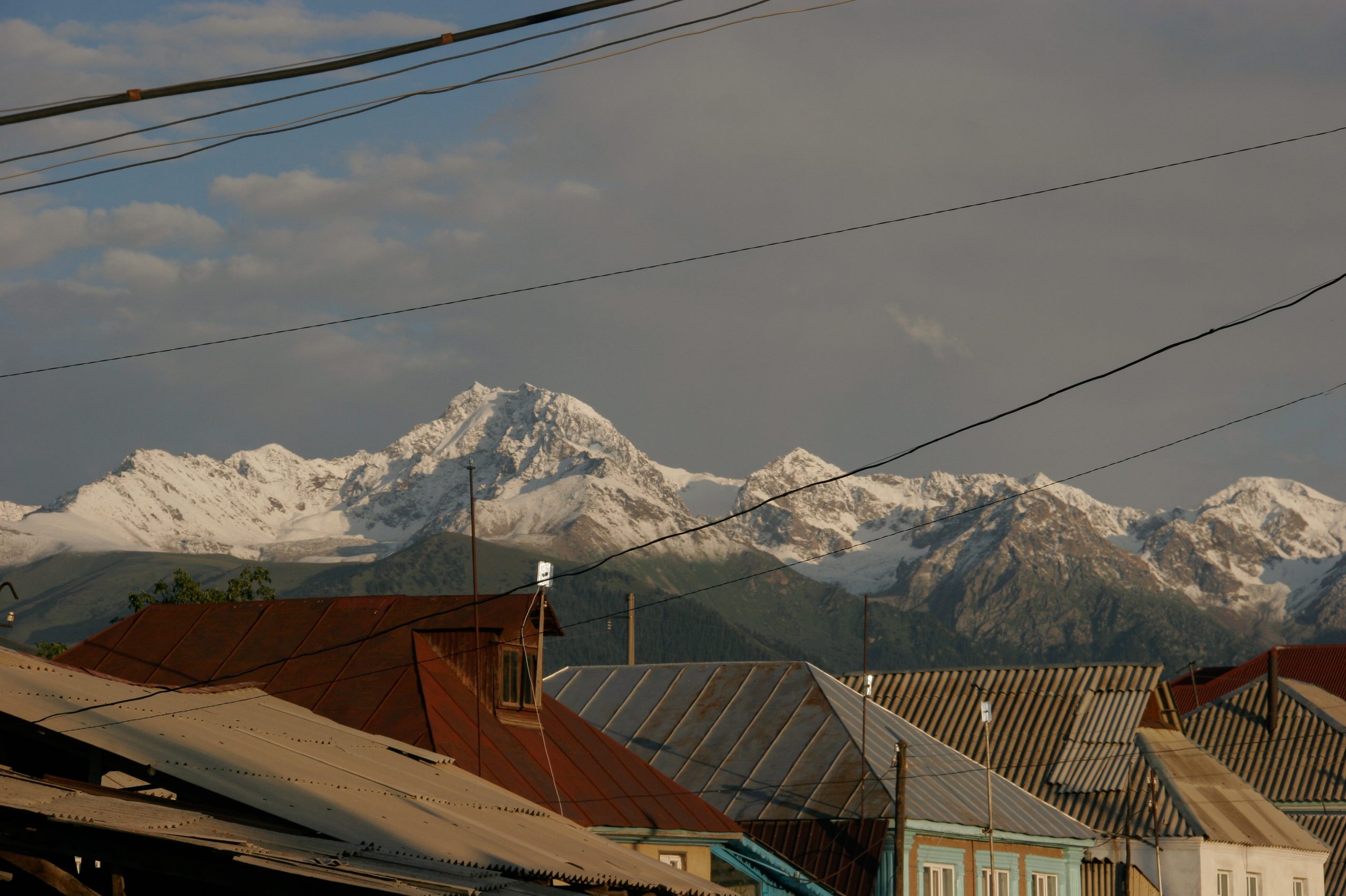 Rusted rooftops of Karakol with fresh snow on the mountains behind
